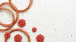 © tonstock - Elegant red and gold mizuhiki knots and circular wired rings arranged on speckled white textured paper evoking festive celebration and joyful charm