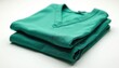 © Viktor - Folded green medical scrubs top laid flat on white background. Clean professional healthcare attire prepared for hospital work. Soft polyester fabric for comfort.