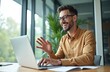© Viktor - Man in glasses smiles at laptop during video call. He talks with colleagues, working in modern office. Remote meeting, business conversation, communication online.