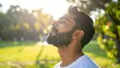 © Matthew - A man stands peacefully in a sunlit park, breathing deeply with greenery around him