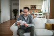 © Migma_Agency - Man relaxing on sofa reading financial mail at home