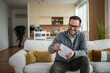 © Migma_Agency - Happy man opening mail at home enjoying positive news