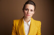 © Alliance - A professional woman in a striking yellow blazer looks directly at the camera with a serious, determined expression, embodying focus and strong business acumen.