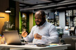 © DC Studio - Black jolly person reading good news after hours on his laptop, cheering and showing his excitement for awesome career opportunity and breakthrough. Proud male celebrating personal target.
