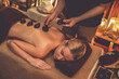© InfiniteFlow - Hot stone massage at spa salon in luxury resort with warm candle light, blissful woman customer enjoying spa basalt stone massage glide over body with soothing warmth. Quiescent