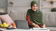 © Prostock-studio - Happy Mature Islamic Lady Using Laptop Taking Notes Working Online Sitting On Couch At Home. Freelance Lifestyle Concept. People And Gadgets. Panorama, Selective Focus