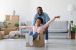 © Prostock-studio - Happy black millennial couple in own home, buyers have fun, laughing on moving day, excited wife riding sitting in cardboard box, husband push it in new house. Relocation, rent and break, indoor