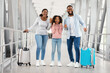 © Prostock-studio - Vacation. Excited African American family of three people having fun and shaking clenched fists, celebrating making winner gesture, travelling together standing in airport terminal hall with baggage