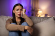 © Home-stock - Sadness concept. Upset woman crying, holding paper tissue and wiping tears, sitting on sofa at home, feeling lonely, free copy space
