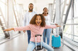 © Prostock-studio - Finally Vacation. Portrait of joyful excited African American girl sitting on baggage and laughing, spreading arms pretending flying, imitating air plane, posing at camera with wide open mouth