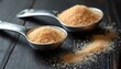 © Vadym - Granulated sugar fills two metal measuring spoons on dark wood. Sweet crystals scatter on table surface. Baking ingredient prep for desserts and pastries.