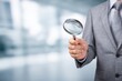 © grey - Business executive holding an empty magnifying glass, symbolizing investigation, search, and scrutiny.