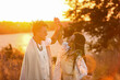 © Pixel-Shot - Young couple of hippies with dreadlocks holding hands in field at sunset