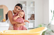 © Pixel-Shot - Young mother wiping her baby with towel after bath at home