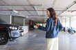 © crizzystudio - Woman using smartphone finding car in underground parking garage