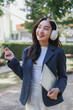 © crizzystudio - Young asian woman listening with headphones holding laptop outdoors