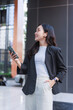 © crizzystudio - Asian businesswoman smiling enjoying wireless technology outdoors
