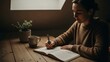 © supra - Woman writing in notebook with cup of coffee and plant on wooden desk