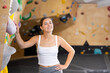 © JackF - Positive slim woman in gym near climbing wall. Active leisure concept. Female coach of climbing department gym, monitors order in hall, closely monitors students, looks into distance