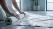 © Alex - Paint wall man carefully rolling up protective sheet on the floor during home renovation preparation.