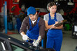 © JackF - Woman with documents looks at guy mechanic fixing car in car service station