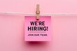 © mik47 - Pink sticky note with 'We're Hiring! Join Our Team' text hanging on a string with a clothes peg, recruitment concept