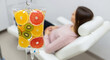 © TanTin - Female patient rests in modern clinic chair, transparent IV drip saline bag with fruits suspended. Vitamin Infusion Therapy, Detoxification concept