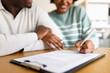 © Daniel - Couple signing contract, mortgage or insurance paperwork at desk. Selective focus.