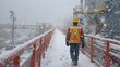 © sablengjago - Worker walks on snowy walkway, industrial setting, cold weather, safety gear, winter scene