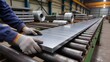 © Наталия Пилипенко - Worker handling a metal sheet on a roller conveyor inside a heavy industry plant, showing steel processing, safety workflow, precision manufacturing and large scale metallurgy