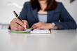 © Lahmz - Close-up of a businesswoman writing in an open notebook with a pen, capturing planning, goal setting, productivity, and personal development in a clean, minimal workspace.
