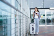 © DG PhotoStock - Female traveler standing at airport terminal with holding smartphone and passport