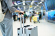 © DG PhotoStock - Close up traveler holding suitcase at airport terminal