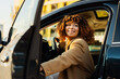 © Maria Vitkovska - Smiling young woman with beautiful curly hair getting into her car, driving and traveling