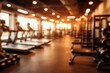 © vxnaghiyev - Blurred gym space with modern sports equipment creating a warm abstract background
