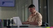 © Marco - Young male employee types focused on laptop at modern office desk during quiet solo work session