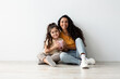 © Prostock-studio - Family Budget. Cheerful Middle Eastern Mother And Little Daughter Holding Piggy Bank While Relaxing On Floor Near White Wall, Smiling Mom And Female Kid Enjoying Economy And Money Savings, Copy Space