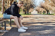 © LIGHTFIELD STUDIOS - Sportive woman rests on a bench in a sunny park during spring workout session