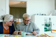 © Davor - Senior couple laughing over breakfast at home kitchen table