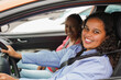 © Sabrina - Young african girl driving a car with mother in background - Family lifestyle, driving licence and transportation concept