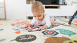 © ADDICTIVE STOCK - Baby exploring on colorful play mat with cards
