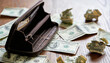 © Николай Чайка - Open leather wallet on wooden table surrounded by crumpled dollar bills, symbolizing financial struggles and economic challenges in personal finance management