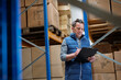 © Halfpoint - Older warehouse worker working looking at document in clipboard.