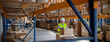 © Halfpoint - Senior woman working in warehouse, wearing reflective vest.
