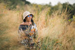 © chokniti - Woman traveler wearing colorful patterned sweater and hat standing in golden grass field under warm sunlight enjoying nature, outdoor adventure, and peaceful autumn atmosphere at countryside