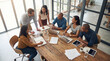 © Nuray - Collaborative Dynamics: A dynamic team of professionals engages in a brainstorming session around a rustic wooden table.