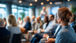 © Laura - Defocused audience listening attentively to presenter in modern conference room, blurred corporate seminar scene, with copy space