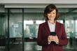 © Stock 4 You - Smiling mature ceo businesswoman investor in suit holding smartphone standing in office, working on device. Middle-aged latin senior business bank manager woman ceo using cell phone mobile. Copy space