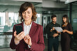 © Stock 4 You - Smiling mature ceo businesswoman investor holding smartphone in office, typing, scrolling and working. Middle-aged latin bank manager woman ceo using cell phone mobile with business people. Copy space