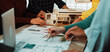 © InfiniteFlow - A vibrant scene depicting a diverse group of architects collaborating on a design project, using blueprints and a physical model during an engaging planning session. SACTR